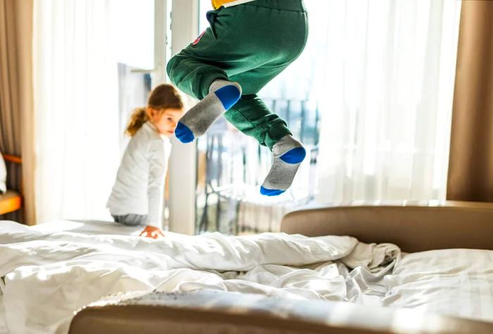 A young child with socks on is bouncing on the bed.