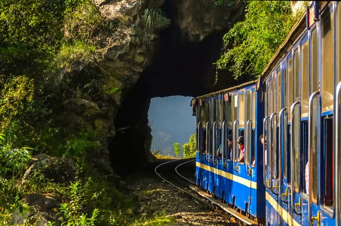 A train from the Nilgiri Mountain Railway exits a narrow tunnel between Mettupalayam and Udagamandalam in South India.