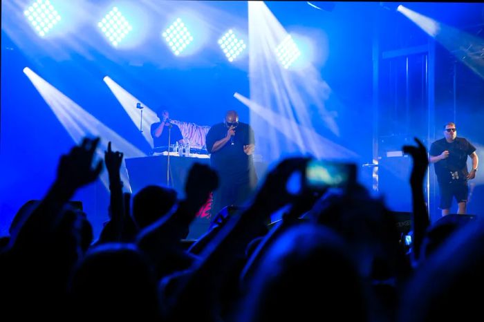 Two performers on stage illuminated by blue spotlights in front of an audience.