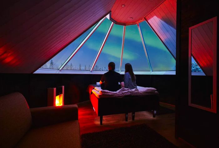 Couple admiring the aurora borealis from an igloo cabin