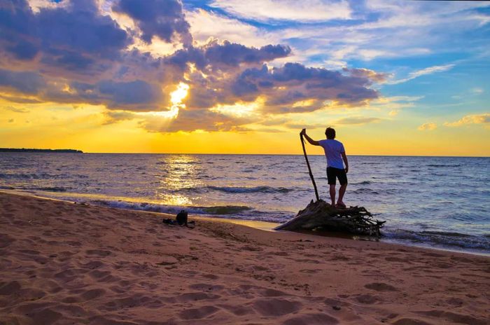 A young man on the beach welcomes the dawn of a new day