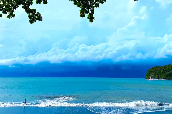 Clouds gather as someone jogs along the beach