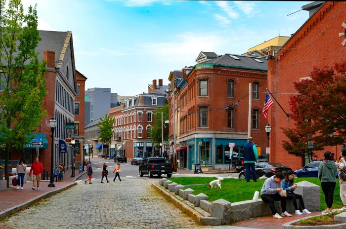 Visitors strolling and socializing in Portland, Maine's Historic Waterfront District, featuring cobblestone streets and red-brick architecture.