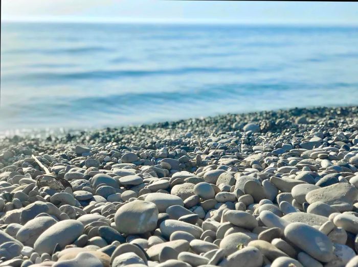 Close-up view of smooth stones at Empire Beach in Michigan, with waves rolling in the distance