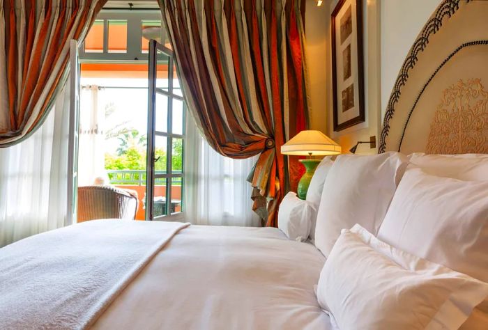 A charming bedroom adorned with crisp white linens and striped curtains.