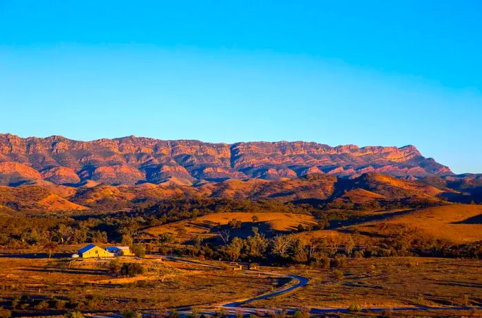 A sunlit yellow building overlooking the majestic Flinders Range of Australia at dusk