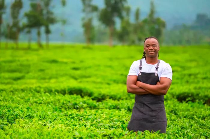 A man stands amidst tall grass on a farm in Kigali, Rwanda