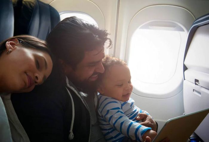 A joyful couple with their toddler seated inside the airplane.