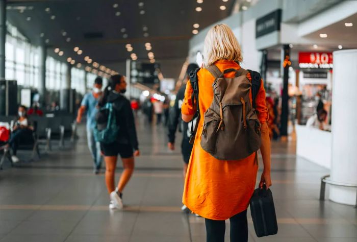 A woman seen from behind at the airport as she heads toward her departure gate.