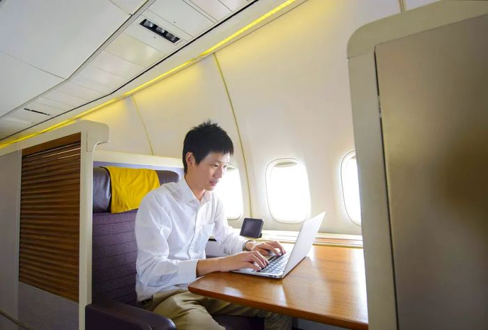 A person working on a laptop during a business class flight