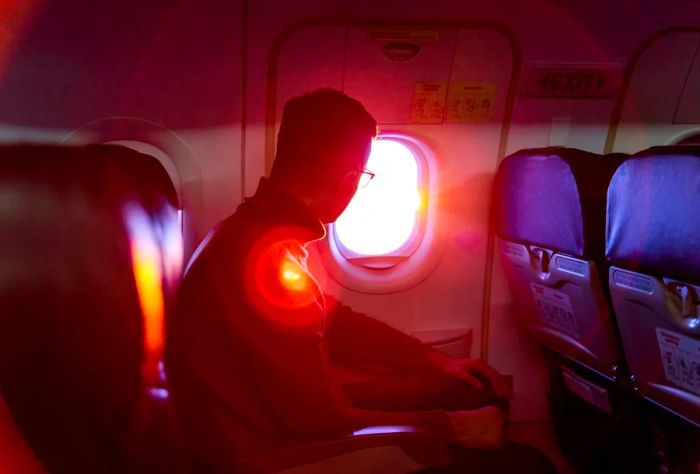 A man sits inside an airplane, gazing at the beautiful sunset through the window.