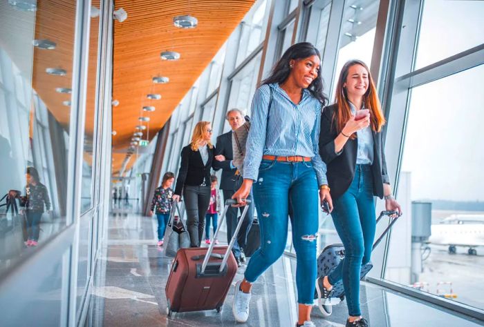 Travelers maneuvering their luggage through an airport terminal.