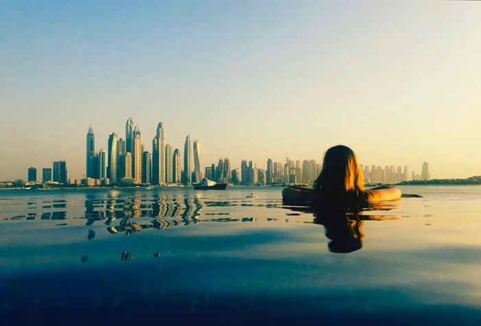 A person relaxes in a pool, gazing at the stunning city skyline.