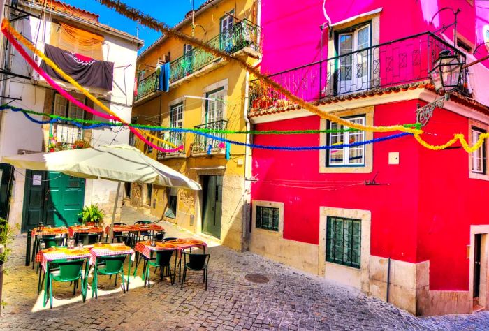 Outdoor dining setup with colorful tableware amidst vibrant houses on a cobblestone street.