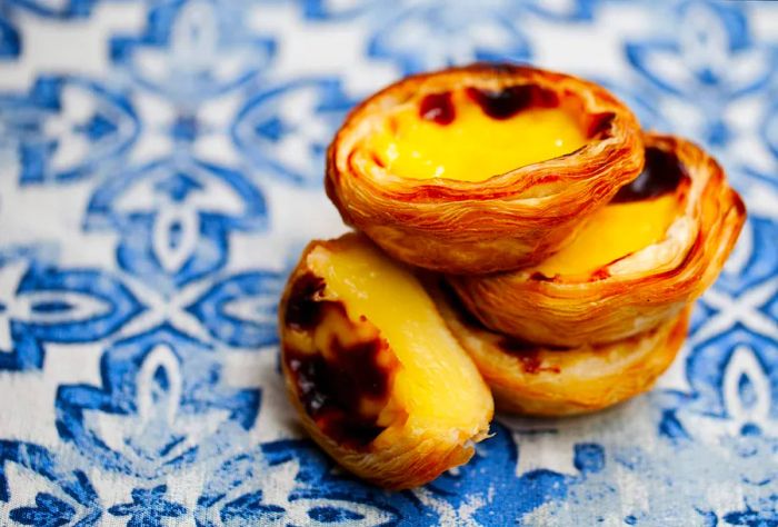 A stack of egg tarts displayed against a blue background.