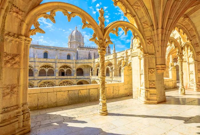 An arched hallway adorned with intricately carved pillars offers views of a distant domed church.