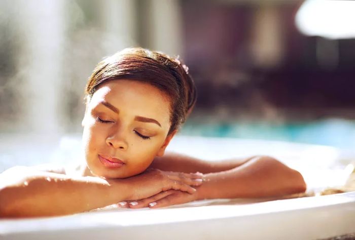 A woman enjoys relaxation in a hot tub with her eyes closed.