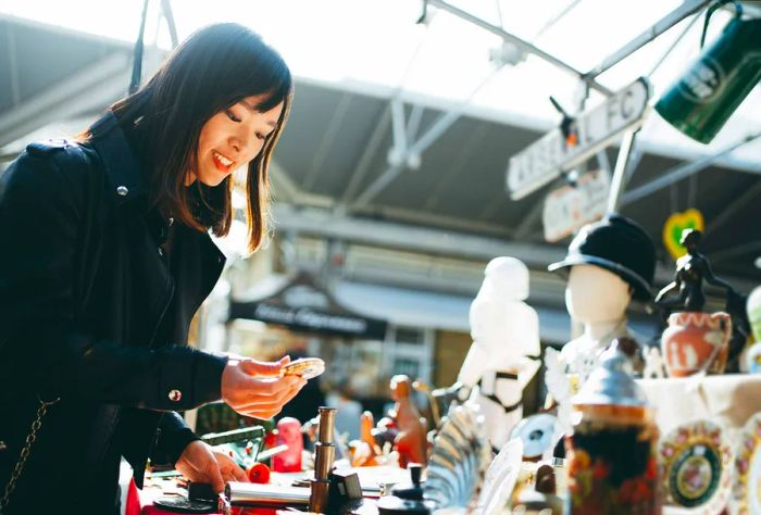 A young woman peruses items at a market display.