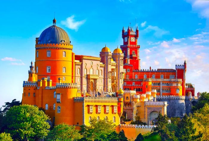 Pena Palace is a striking and colorful castle perched on a hilltop, showcasing vibrant yellow and red tones, with domed towers surrounded by crenellated walls and a clock tower adorned with turrets.