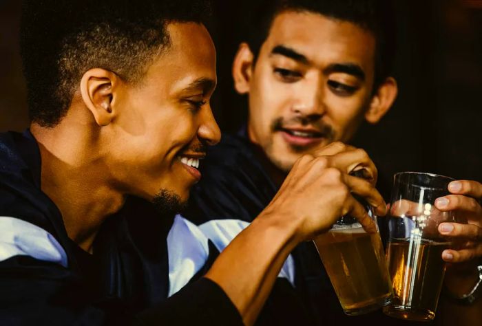 Two men raising their beer glasses in a toast.