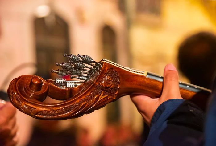 A hand skillfully playing the strings of a beautifully crafted guitar.