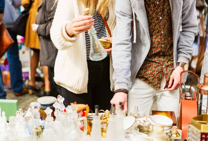 Two people browsing through vintage items at a flea market.