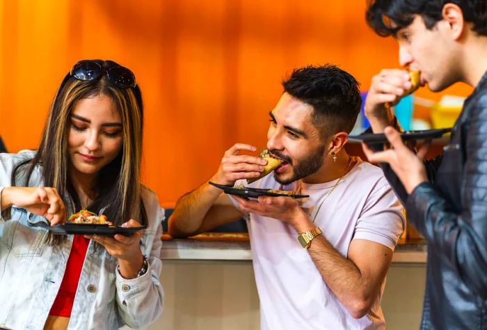 Three friends enjoy tacos at a taqueria.