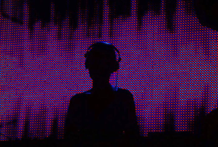 A DJ's silhouette illuminated by neon lights in a nightclub setting.