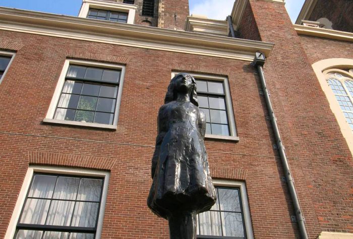 A statue of Anne Frank stands proudly in front of the Anne Frank House in Amsterdam, Netherlands.