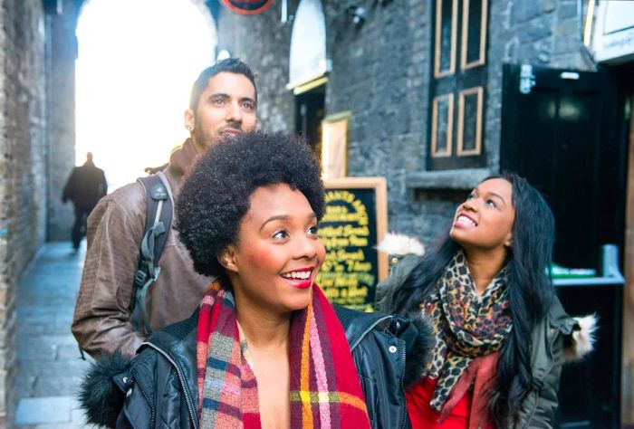 Three individuals exploring a narrow alleyway.