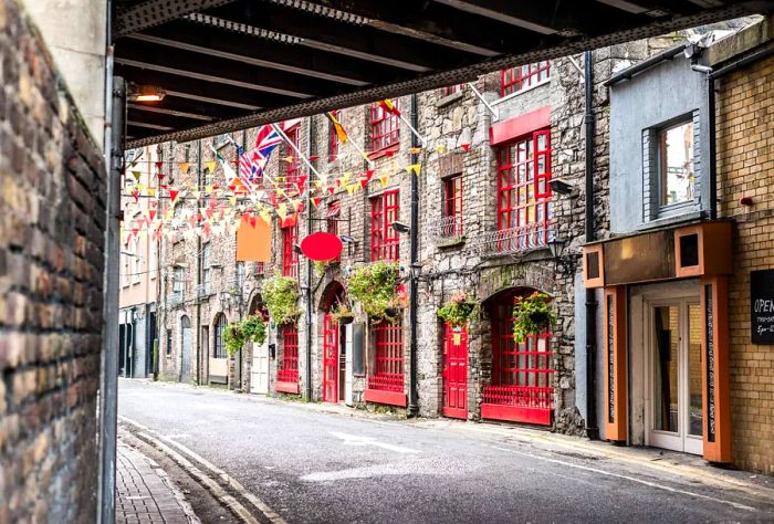 A quaint street flanked by brick buildings adorned with festive string lights.