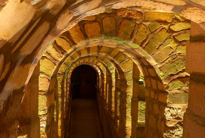 Stone arched tunnel within the Paris Catacombs, France