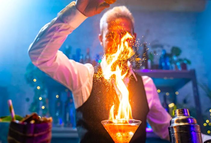 A flaming cocktail served by a bartender.