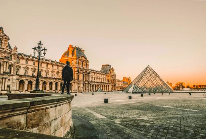 A man gazes at the glass pyramids of the Louvre Museum, Paris, France