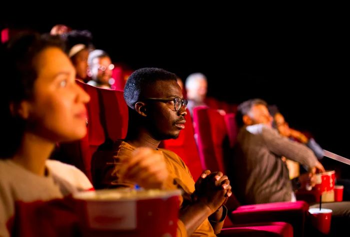 An African-American man enjoying a film at the cinema.