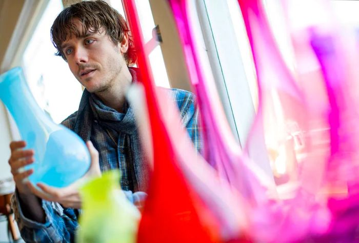 A man examines a light blue bottle in a shop.