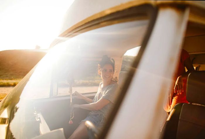 A female passenger stepping out of a van as seen from the vehicle's windshield.