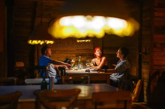 A glimpse of a dimly lit restaurant, featuring three diners seated at a table.