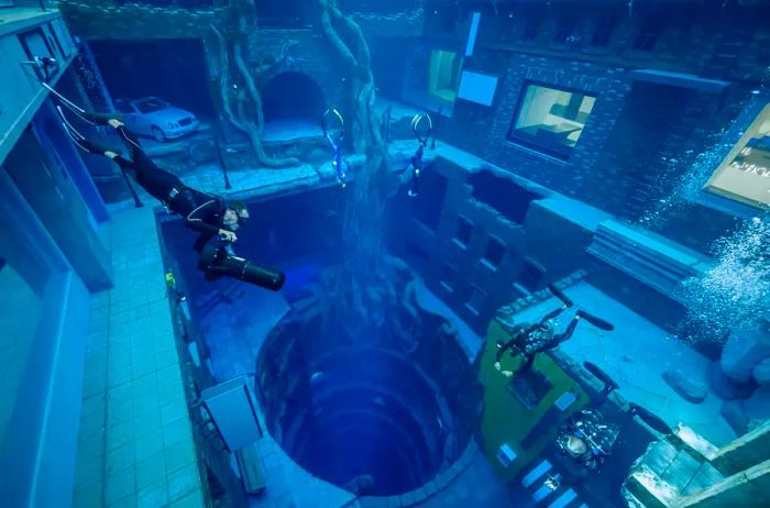 A person equipped with a large camera swims in the deep pool at Deep Dive Dubai