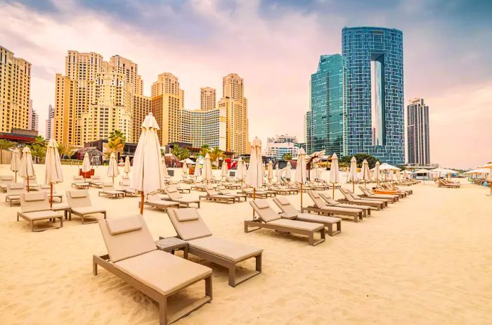 Vacant lounge chairs with umbrellas and sunbeds at JBR Beach in Dubai. A prime travel and vacation spot in the United Arab Emirates