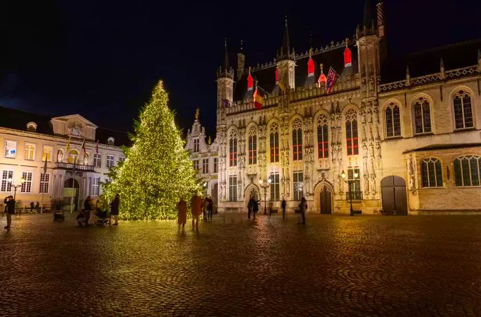 This image depicts the Christmas tree located in the square in front of Bruges' town hall, the oldest in the Benelux region, finished in 1421.