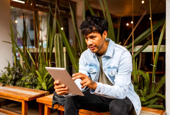 A man sitting in a café, browsing on an iPad.