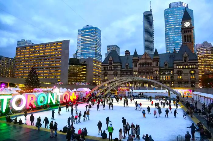 People enjoying ice skating at an outdoor rink in Nathan Phillips Square, downtown Toronto, Ontario