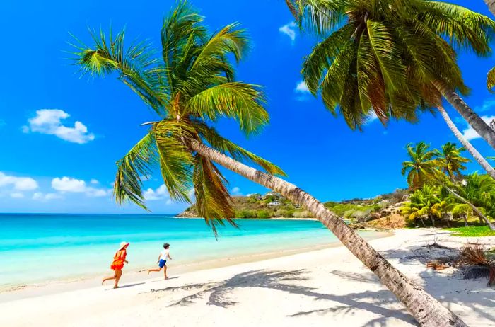 A joyful mother playfully chasing her young son along a tropical beach in Antigua, Leeward Islands, Caribbean, West Indies