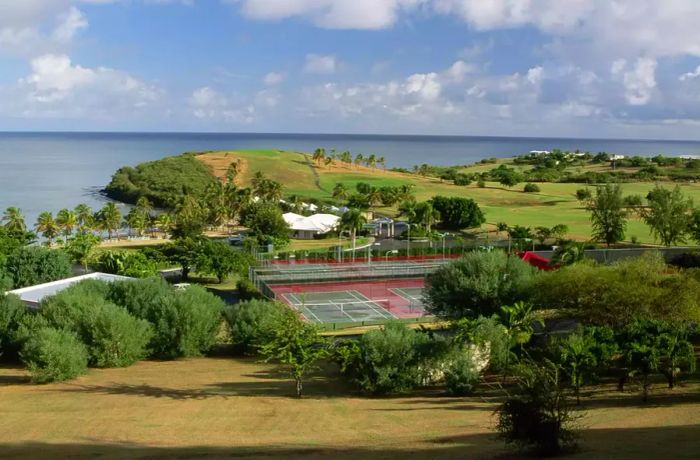 A scenic view showcasing the ocean, golf course, and tennis courts at Buccaneer Golf Course.