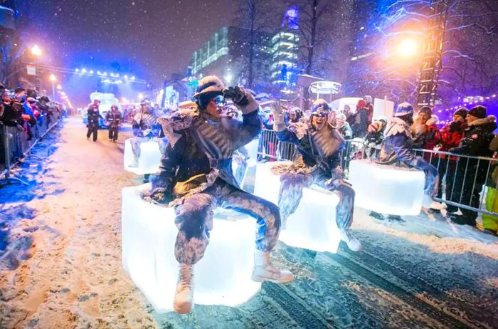 Performers in a nighttime parade dance on blocks of illuminated ice during the Carnaval de Québec.