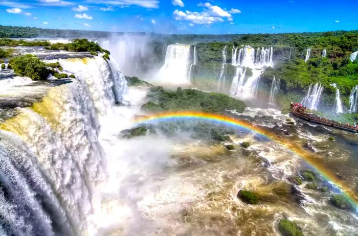 Aerial view of Iguazú Falls featuring a rainbow above the cascades.