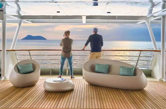 Two individuals admiring the ocean view from the observation deck of the National Geographic Islander II