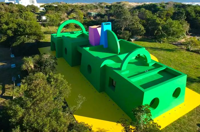 A vibrant artist residency building in shades of green, yellow, blue, and purple located in Uruguay.