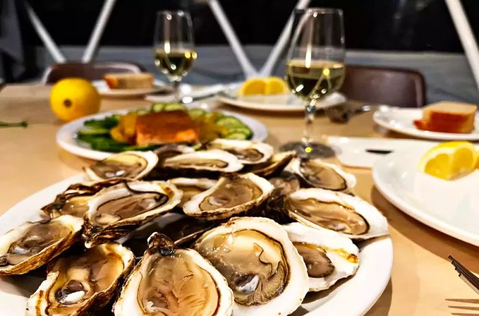 A table set with a plate of oysters and glasses of wine